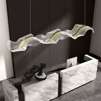 Modern luxury chandelier with wavy glass design and gold accents above marble reception desk