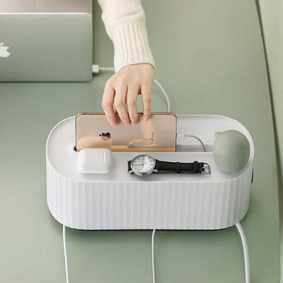 White power strip cable organizer box with phone, watch, and earphones on top for neat cable management